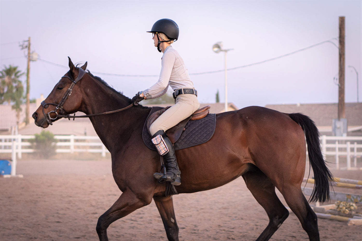 Woman riding a brown horse and wearing a plaid cell phone case