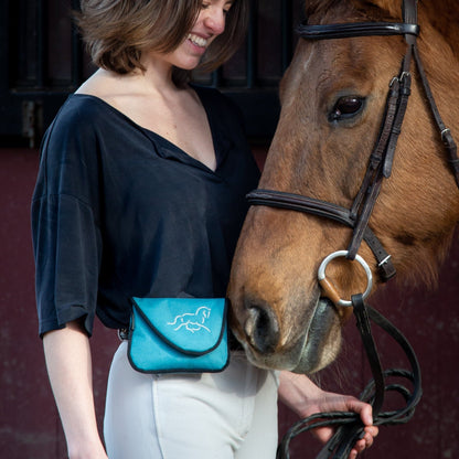 Woman wearing a teal horse treat training bag with brown horse